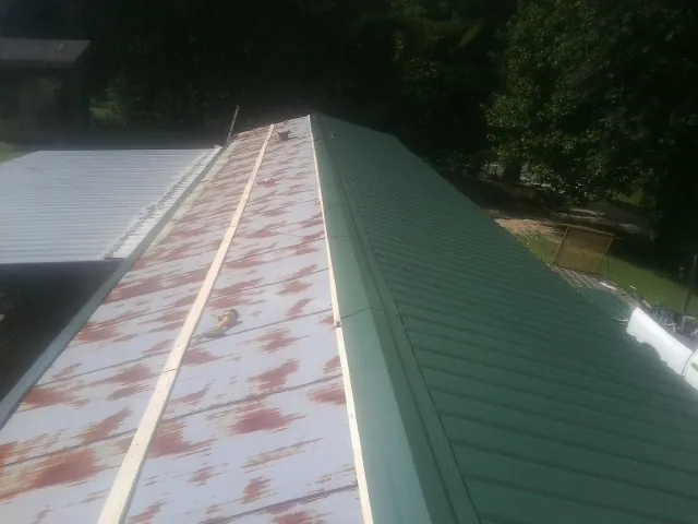 Old rusted panels beside newly installed green metal roofing — Wind Damage Roof Repair by Roofing Brothers in Southport