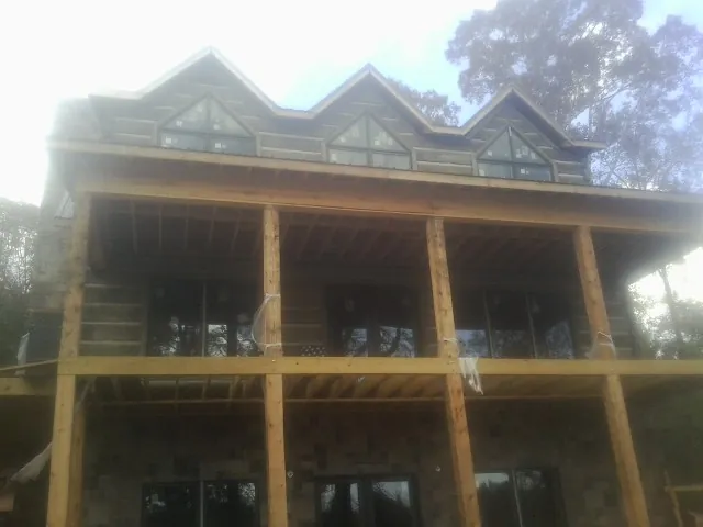 Dormers and porch framing on a large log home under construction — Roof Coating work by our crew in Southport